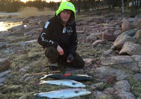 Filip med dagens fångst av fisk på klipporna