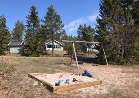 Precis invid stugorna ligger lekplatsen med sandlåda, gungor och lekstuga